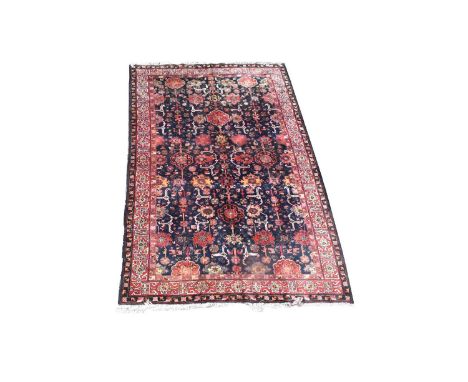 A Tetex carpet, with stylized flowerhead design on dark blue ground, 289 x 193cms.