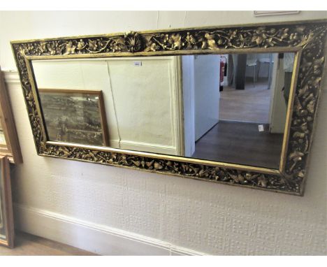 Reproduction carved gilded rectangular wall mirror with shell surmount, 25ins x 55ins 