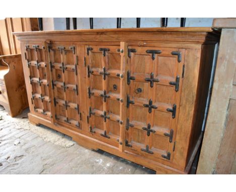 Modern oriental hardwood and iron mounted side cabinet with two pairs of panelled doors on bracket feet, 62ins wide 