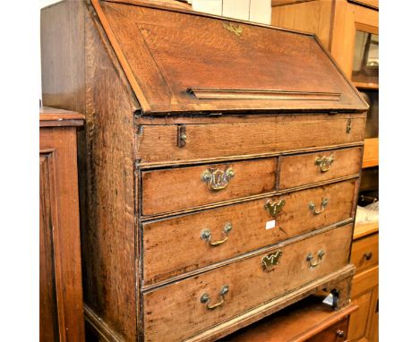 18th Century oak bureau, the fall front enclosing a fitted interior above two short and three long drawers with brass handles