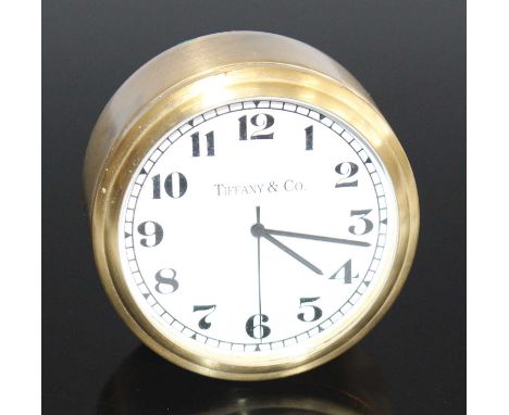Tiffany &amp; Co - a small gilt brushed metal bedside clock, having white enamel dial titled Tiffany &amp; Co, removable cove