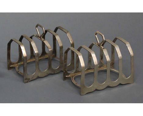 A pair of Art Deco silver four division toast racks, each of plain form with angular central carry handles, maker Harrison Br