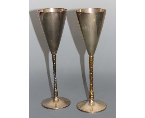 A pair of silver wine goblets by Stuart Devlin (1931-2018) , each of plain conical form, raised on naturalistic gilt stems, o