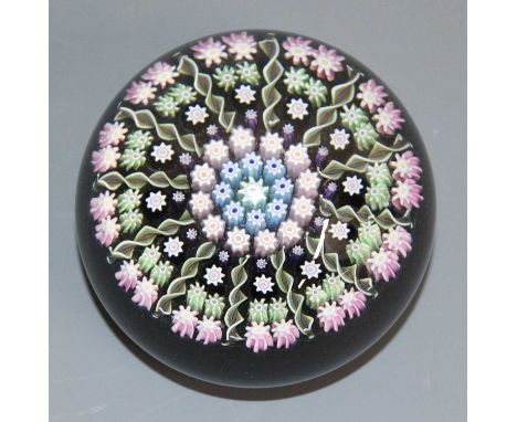 A Perthshire millefiori glass paperweight, the interior stemmed canes including spiral twist examples, the centre cane marked