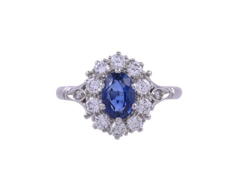 A SAPPHIRE AND DIAMOND CLUSTER RING LONDON 1981The oval cut sapphire within a surround of brilliant cut diamonds, to trifurca