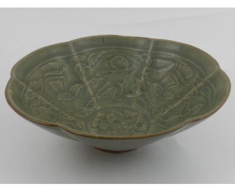 A Chinese Longquan ware style celadon bowl, decorated with children playing amongst stylised flowers. D.19cm