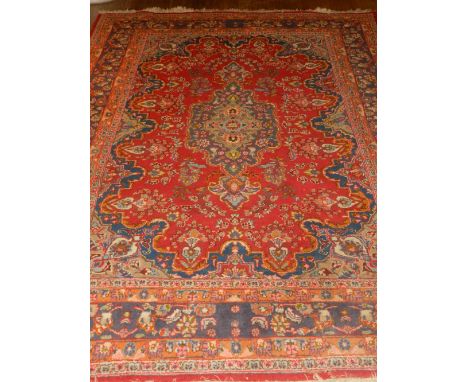 A red ground Kashan carpet, having floral pear drop medallion to centre within floral borders, fringed. L.284cm W.190cm