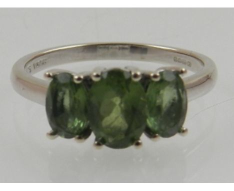 A 9 carat white gold and green apatite three stone ring. 