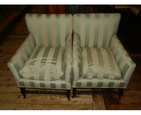 A pair of early 20th century oak framed armchairs, upholstered in a green and cream striped fabric, raised on turned bobbin s