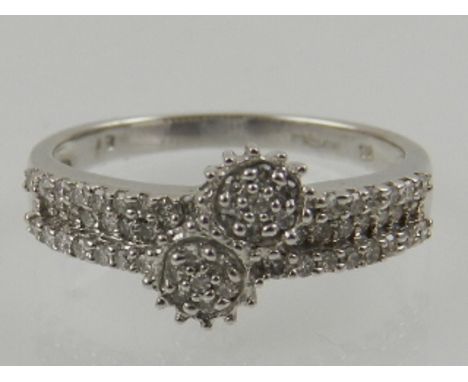 A 9 carat white gold and diamond crossover cluster ring.