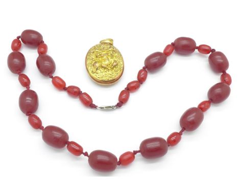 A gilt metal portrait locket and a red coloured bead necklace