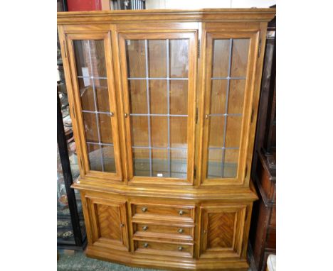 A Drexel Chartwell library bookcase, outswept cornice above three glazed doors enclosing adjustable shelves, the base with th
