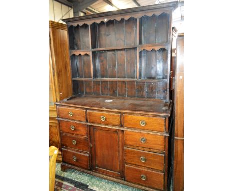 An early 20th century oak farmhouse dresser, outswept cornice above a shaped apron and an arrangement of segmented plate rack