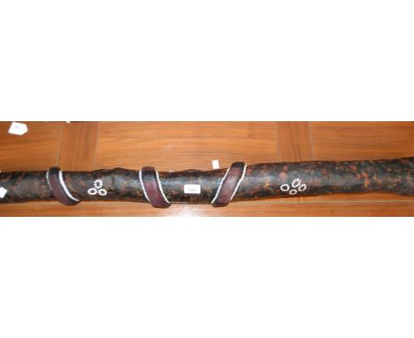 An Australian didgeridoo, typically constructed of termite-bored hardwood, carved in relief with a snake and painted with dot
