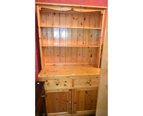 A 20th century pine dresser, oversailing cornice above two adjustable shelves, the base with two short drawers above a pair o