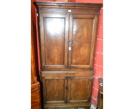 A 19th century elm floor standing corner cupboard, outswept cornice above a pair of panel doors enclosing two shaped shelves,