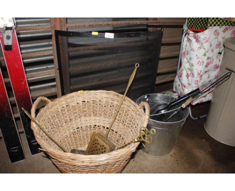 A wicker log basket; a brass chestnut roaster; brass cream skimmer; brass toasting fork; a wire spark guard; coal bucket and 