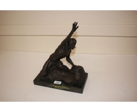 A bronze study of a nude male holding his hand aloft