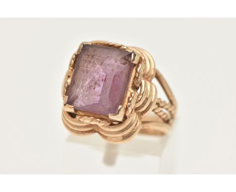 A 9CT GOLD AMETHYST RING, set with a rectangular cut amethyst, four claw set to a stepped scallop surround, trifurcated shoul