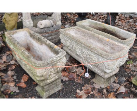 A PAIR OF RECTANGULAR WEATHERED COMPOSITE GARDEN PLANTERS, with mythical creature and human mask details to all facets, width