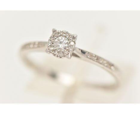 A 9CT WHITE GOLD DIAMOND CLUSTER RING, set with a central round brilliant cut diamond, claw set within a surround of single c
