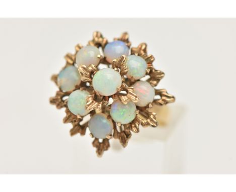 A YELLOW METAL OPAL SET CLUSTER RING, large floral design set with nine circular cut white opal cabochons, each claw set, tex