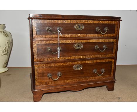A SAMPLE/APPRENTICE CHEST OF DRAWERS with three drawers decorated with a lighter wood band, each with two brass movable handl