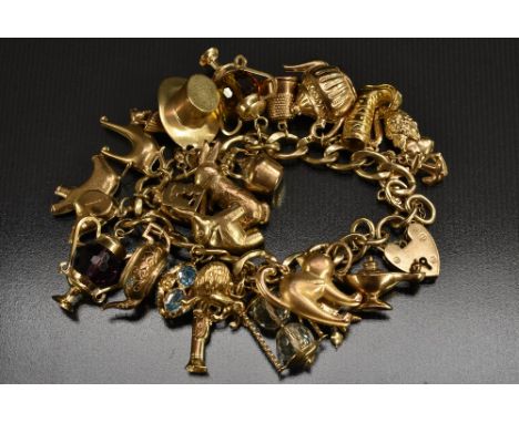 A 9ct gold flat curb charm bracelet, suspending twenty three assorted 9ct gold and yellow metal charms inc Elephant, oil Lamp