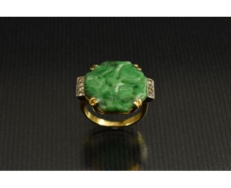 A carved jade and diamond ring, central octagonal jade panel carved with a flowers, between four stone diamond accented shoul