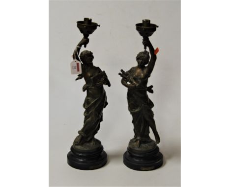 After Moreau, a pair of late 19th century spelter figural lamp bases, each in the form of a lady in standing pose with arm al