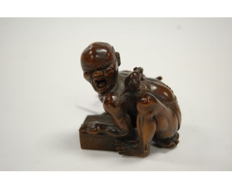 A Japanese Meiji period softwood netsuke, carved as a man in kneeling pose with rat upon his back, h.6cm.Two toes chipped off