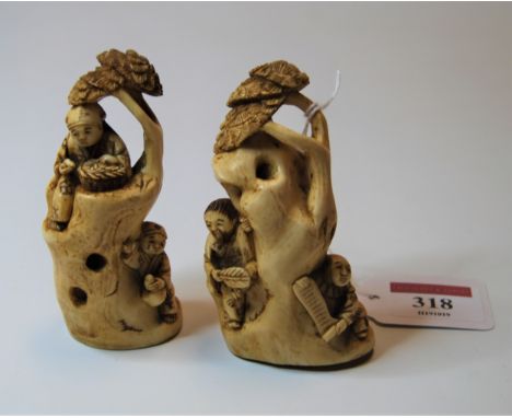 A pair of Japanese okimono, each carved as two figures around a tree trunk, h.9cm