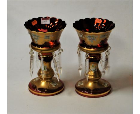 A pair of early 20th century Bohemian style ruby glass and gilt overlaid table lustres having applied floral decoration with 