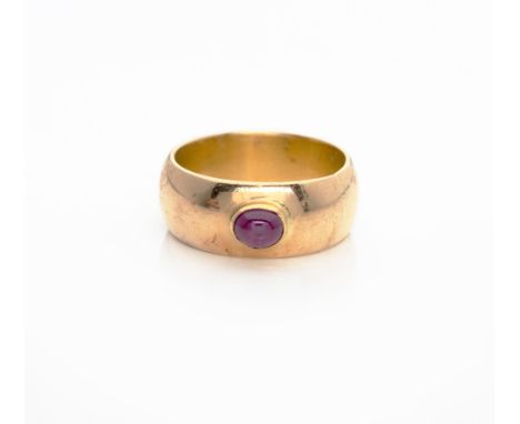 Designed as a broad domed band bezel set to the centre with an oval cabochon ruby, possibly enhanced, in 18ct gold, ring size