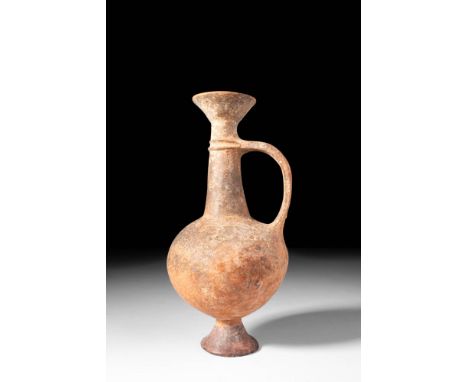 Ca. 1500 - 1300 BC.
An apple-shaped body bilbil with a slender cylindrical neck, a strap handle, and a flared rim. A moulded 