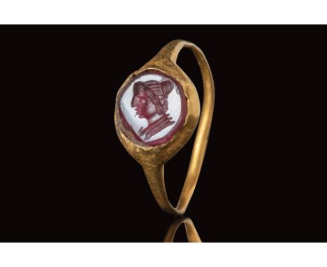 Ca. AD 100 - 300.
A gold ring with a round hoop enlarged on the shoulders to form a round bezel securing a red carnelian inta