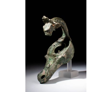 Ca. AD 100 - 300.
A cast bronze oil lamp with a pear-shaped body leading to a curvaceous spout. The lamp features an impressi