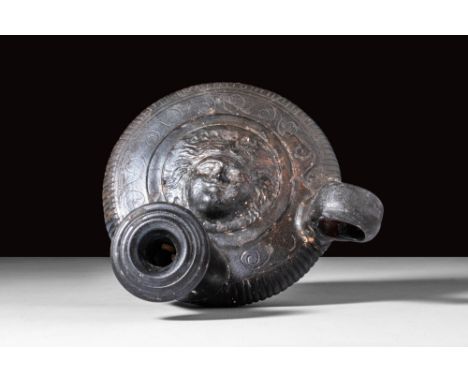 Ca. 350 - 300 BC.
A black-glazed pottery guttus (or guttos, oil-lamp filler) bearing the feminine face of a gorgon atop the t