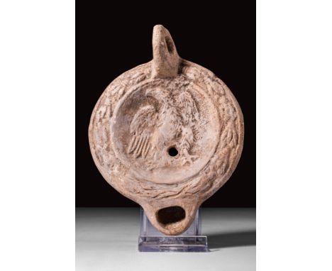 Ca. AD 50 - 200.
A mould-made round terracotta oil lamp with a convex lower part and a flat top. In the concave disc, there i