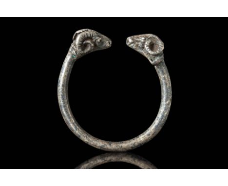 Ca. 400 - 300 BC.
A silver ring with an open-ended front featuring decorative ram head terminals on either side of the openin