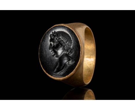 Ca. AD 100 - 200.
A gold ring with a circular band that supports a bezel set with black jasper. The jasper is intricately car