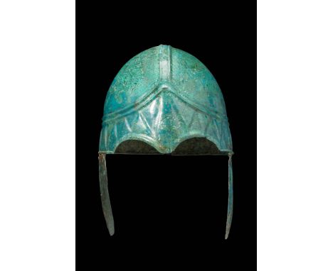 Ca. 500 BC.
A striking Chalcidian bronze helmet with two curved cheek pieces attached with iron pins that form a hinge.The fo