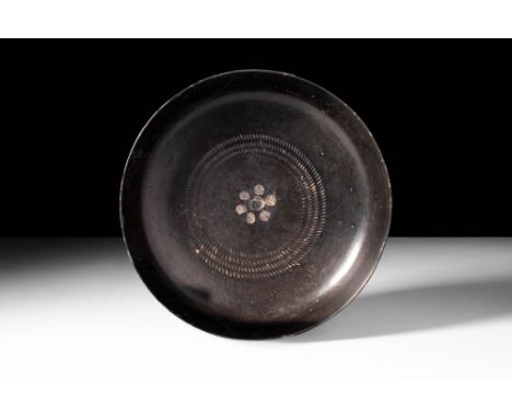 Ca. 400 - 300 BC.
A stunning blackware patera with a classic form. The tondo of the shallow bowl is impressed with six stylis