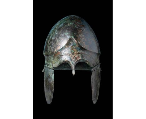 Ca. 500 BC.
A striking Chalcidian helmet comprised of hammered bronze. This helmet is distinguished by its curved cheekpieces