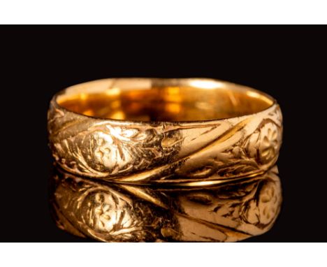 Ca. AD 1400 - 1500.
A medieval gold ring with a decorated hoop, engraved with floral motifs alternating horizontal bands. The