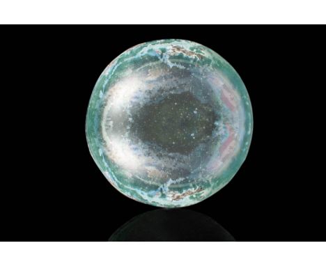 Ca. AD 100 - 300 .
A shallow glass bowl in colourless glass with a pale blue-green tinge. The bowl has concave sides, with an