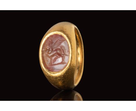 Ca. AD 100 - 300.
A gold ring with a D-section round hoop enlarged on the shoulders to form a round bezel securing a carnelia