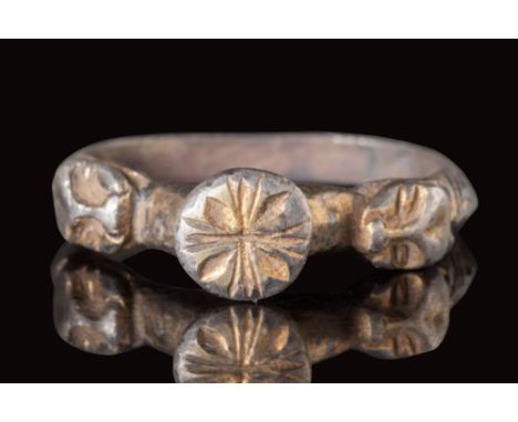 Ca. AD 1300 - 1500.
A silver gilt ring with a polygonal section hoop embellished with engraved geometric motifs and lion-shap