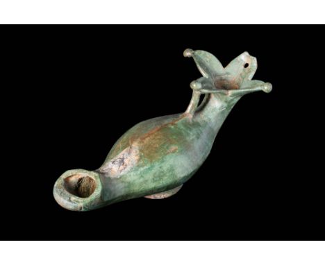 Ca. AD 100 - 300.
A cast-bronze oil lamp depicting a pomegranate flower at the end of the handle. The elongated, pear-shaped 