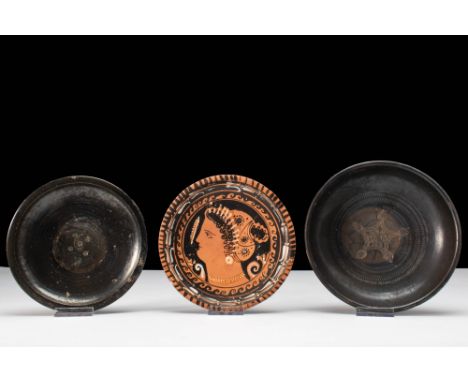 Ca. 400 - 300 BC.
A collection of three South Italian dishes, two black glazed with a protomorphic geometric motifs stamped t